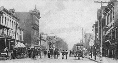 Main Street, looking east, during the 1890s. The Mast Department Store appears at left, and beyond it the Thompson Building at the corner of Second Avenue.