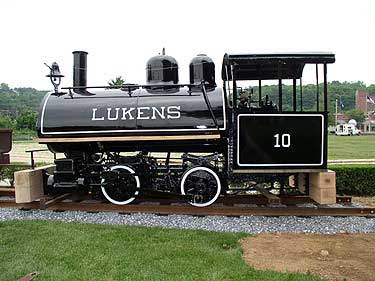 The restored locomotive sitting on its railroad bed with 4 narrow gauge flat cars.